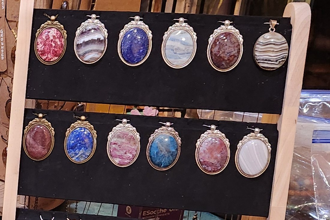 Oval stone pendants in decorative frames on a display stand